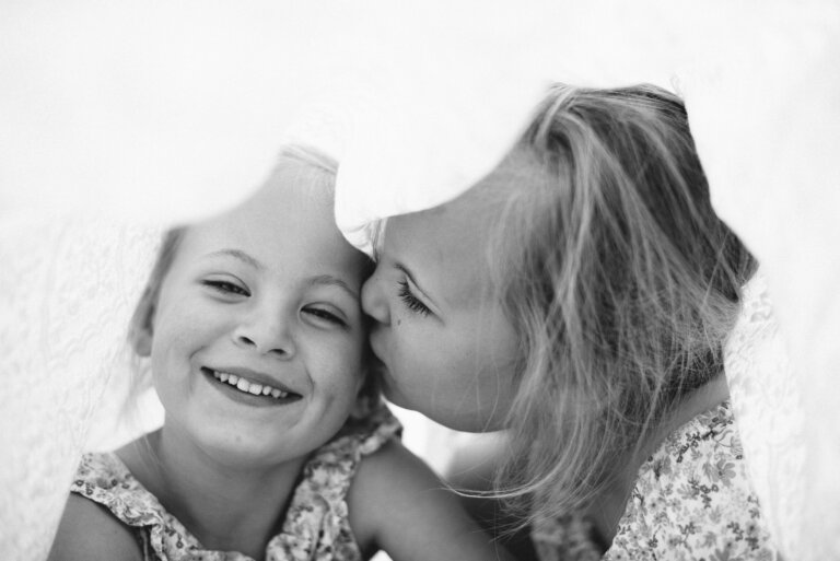 Sibling playing under a blanket 768x513